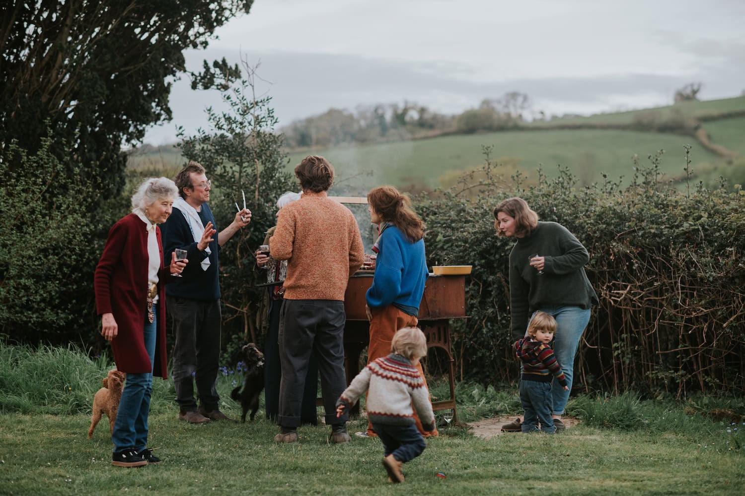 Family enjoying outdoor gathering on a Dorset coast garden with scenic hills and greenery.