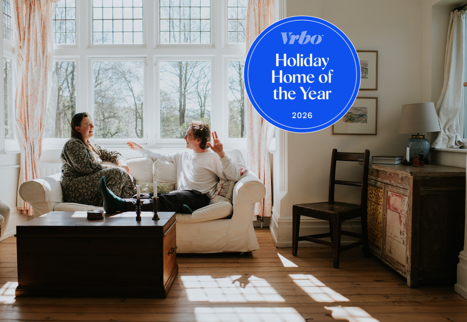 Two young people earnestly chatting on a sofa in the sitting room in front of the garden window